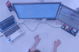 Programmer coding at desk with dual monitors