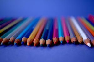 A row of colored pencils on a blue surface