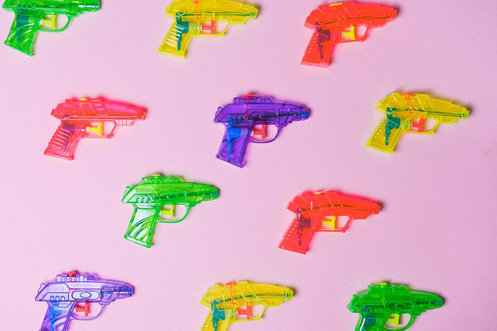 A colorful pattern of water guns on a pink background