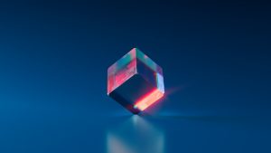 A crystal cube with a rainbow reflection sits on a blue surface