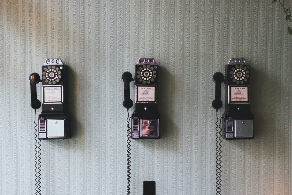 three old cable phones on the wall